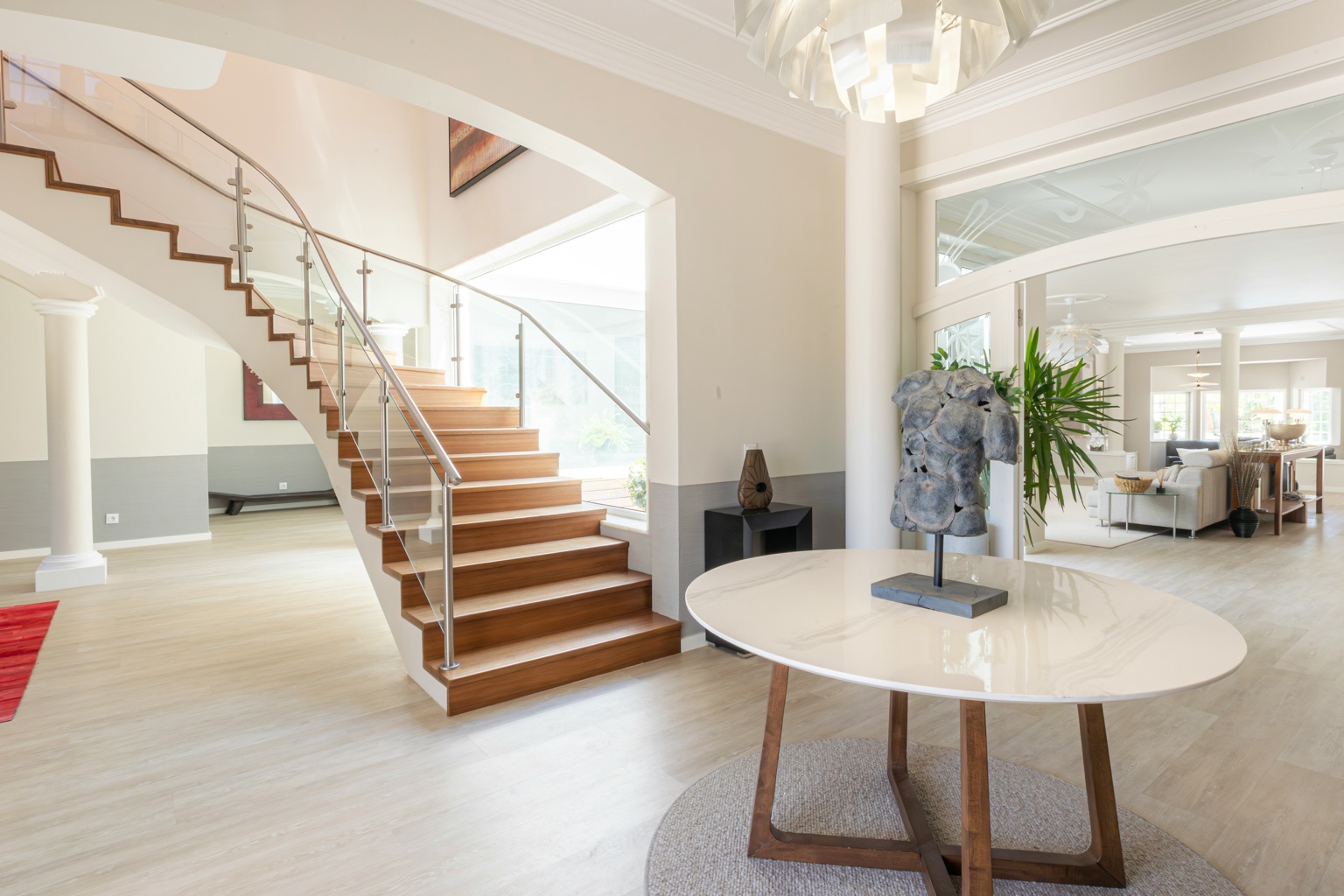 Elegant luxury home interior with sculptural wooden staircase and glass railing